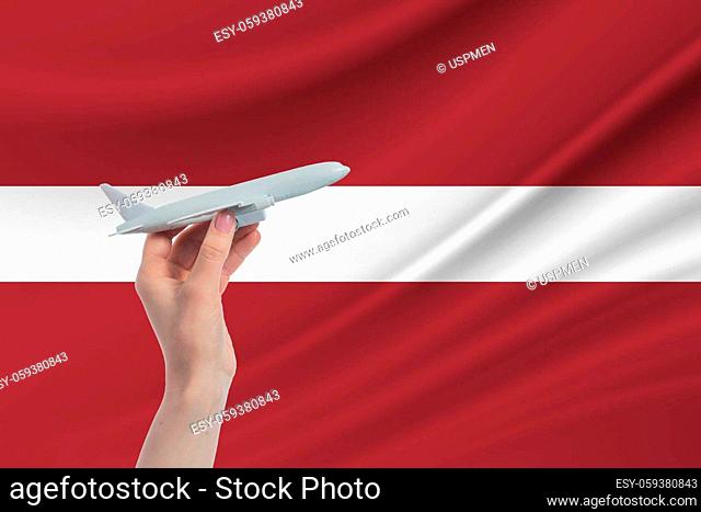 Airplane in hand with national flag of Latvia Travel to Latvia