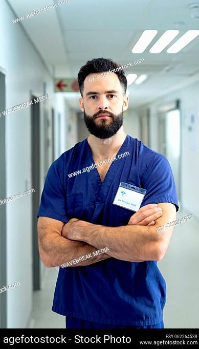 Vertical portrait of serious caucasian male healthcare worker in hospital corridor, copy space