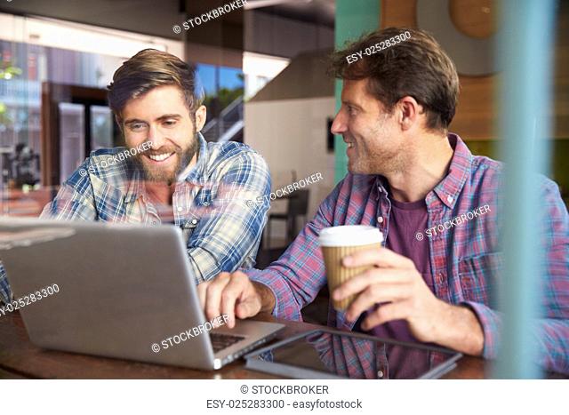 Two Businessmen Working On Laptop In Coffee Shop