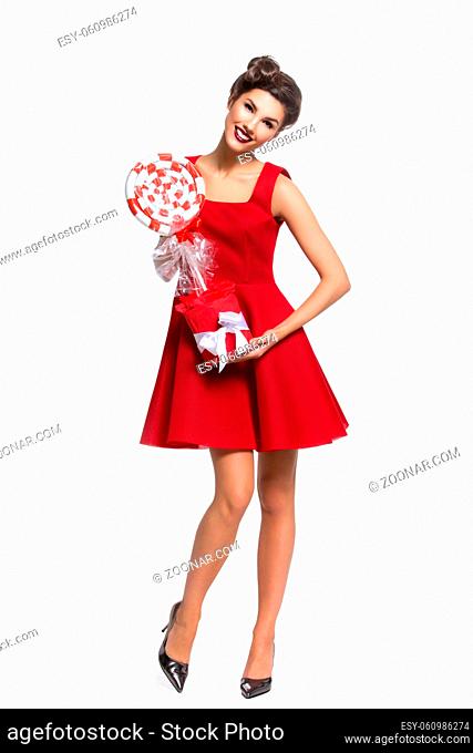 Beautiful young woman in red dress with big candy. Isolated over white background. Copy space