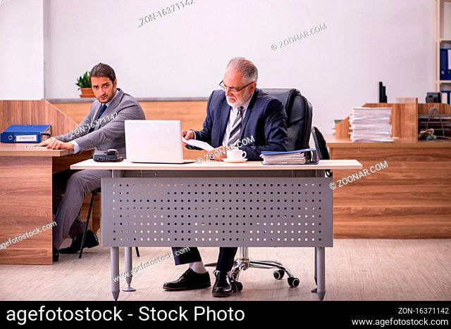 Old male boss and young male assistant in the office