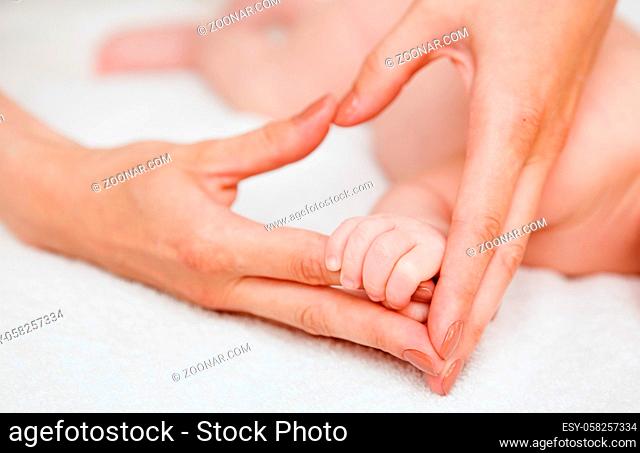 Baby holding mother finger and together form a heart shape by hand