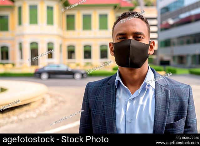 Portrait of young African businessman with mask for protection from corona virus outbreak in the city streets outdoors