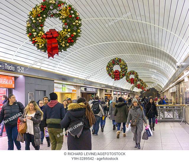Dashing commuters travel through the LIRR concourse underneath Christmas decorations in Pennsylvania Station in New York on Thursday, December 20, 2018