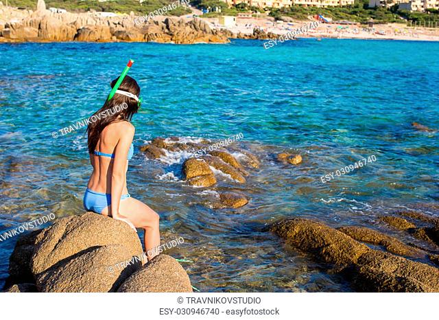 Young beautiful woman with snorkeling equipment on stones