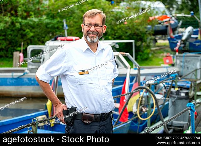 PRODUCTION - 04 July 2023, Hamburg: Swan father Olaf Nieß stands on a pier in front of his boats in the swan quarter. For 27 years