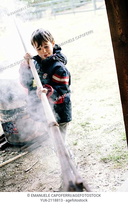Child draws a strip of wood by boiling, Ispra, Varese, Italy