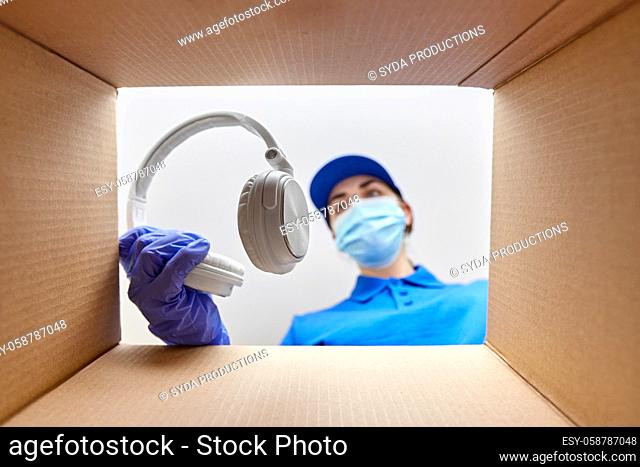 woman in mask packing headphones into parcel box