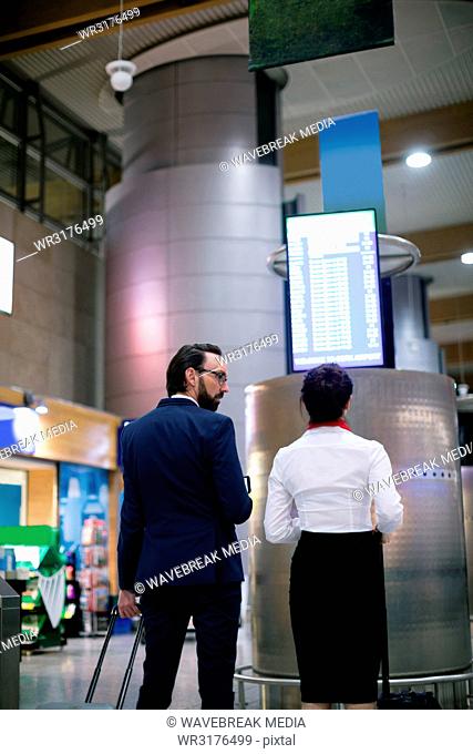 Businessman and woman looking at departure board