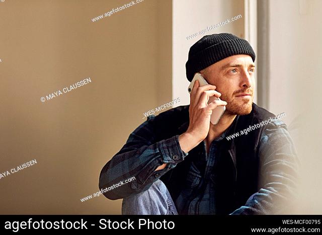 Man refurbishing shop location, sitting on windowsill, talking on the phone