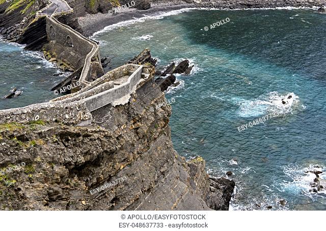 Stone bridge and narrow cliff trail above the Bay of Biscaya on the islet of San Juan de Gaztelugatxe, Bakio, Costa Vasca, Bay of Biscay, Basque Country