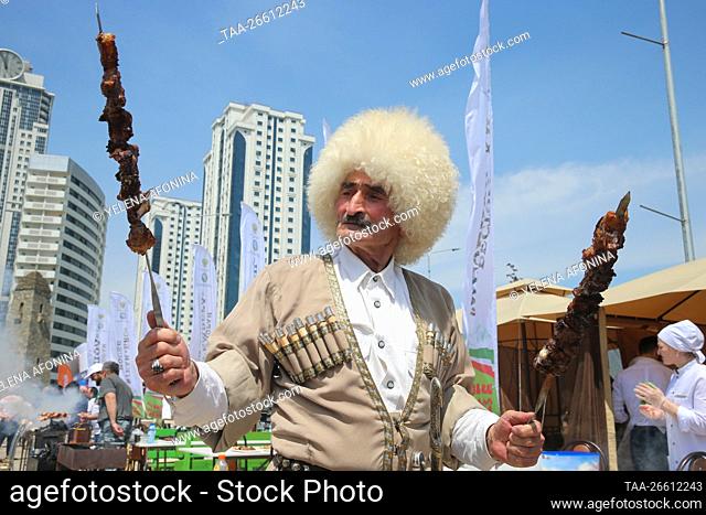 GROZNY, RUSSIA - MAY 5, 2018: A man in a traditional Chechen costume cooks shashlik [a meat dish similar to mutton kebab] at the Shashlyk-Mashlyk international...