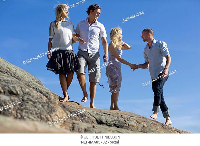 Two couples walking together on rock
