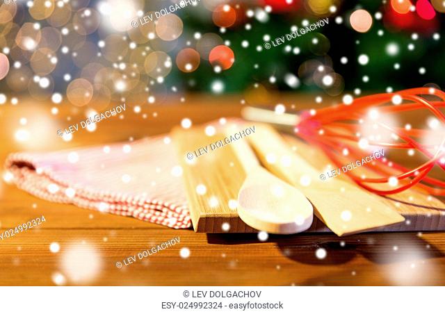baking, cooking, christmas and food concept - close up of kitchenware set and towel on wooden cutting board at home kitchen