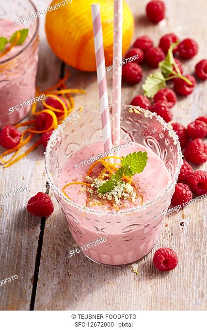 Raspberry and orange milkshakes in glasses with fresh berries and straws