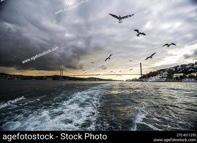 Bosphorus Bridge spanning over Bosphorus Strait connecting Europe and Asia. Bosphorus Sunset Cruise on an overcast day. Istanbul, Türkiye (Republic of Türkiye)