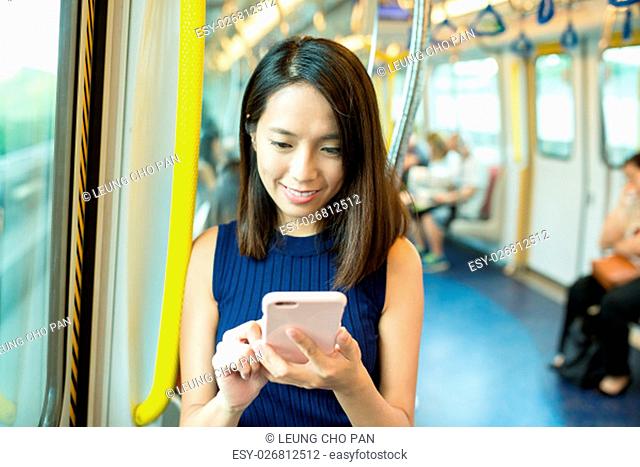 Woman using cellphone inside MTR in Hong Kong