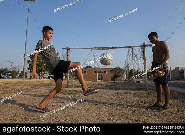 16 March 2023, Argentina, Rosario: Two boys play in front of a broken goal on a soccer field in the poorer neighborhood of Los Pumitas in the hometown of soccer...