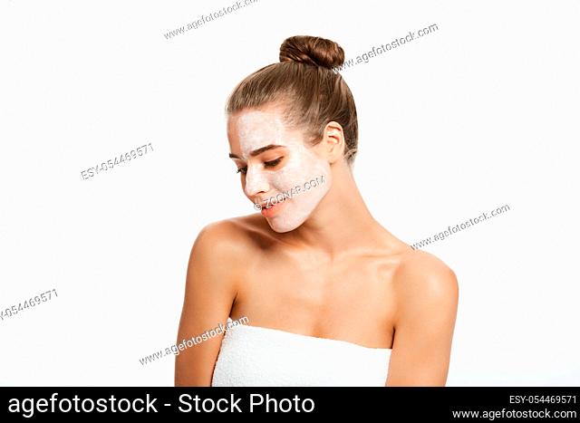 Woman with lifting cream applied on a half of her face, isolated on white