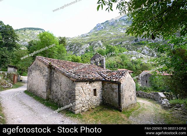 07 August 2020, Spain, Bulnes: The parish church of San Martin, built of quarry stone in front of the limestone cliffs in the Picos de Europa National Park