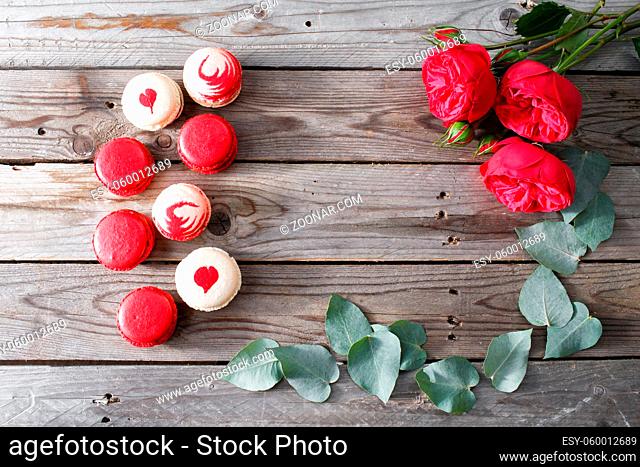 Red macaroons desserts and roses on wooden background. dessert for breakfast on Valentine's Day. copy space