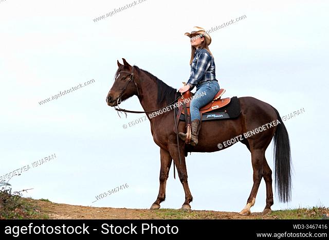 Side view of a young cowgirl riding her horse