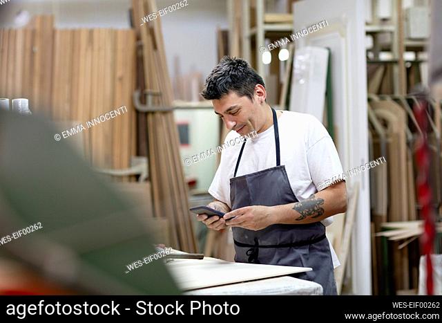 Male artist using mobile phone while standing at workshop