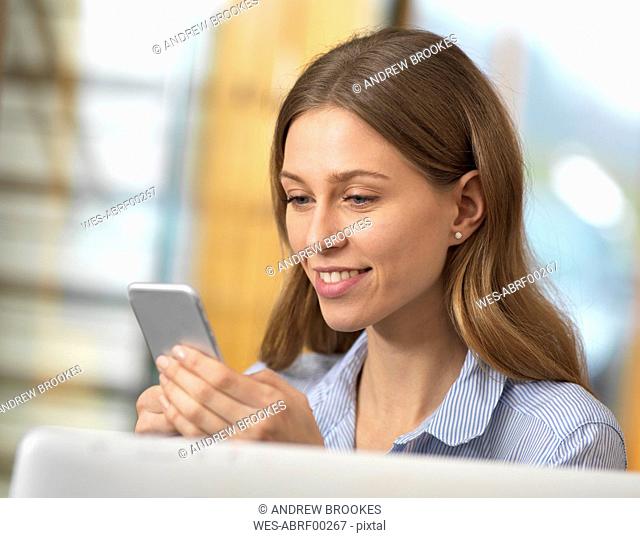 Smiling businesswoman using cell phone in office