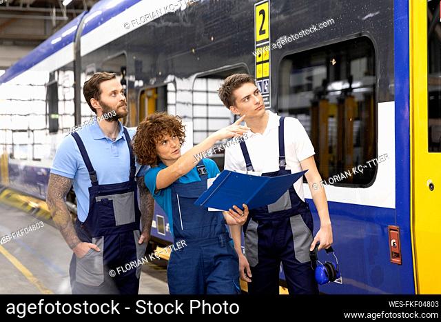 Engineer with trainees pointing at monorail in industry