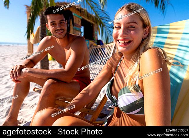 Caucasian couple sitting on deck chairs at the beach