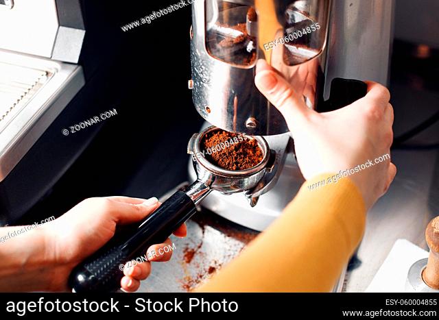 small business, people and service concept - woman or waiter in apron with holder and tamper preparing coffee at coffee shop