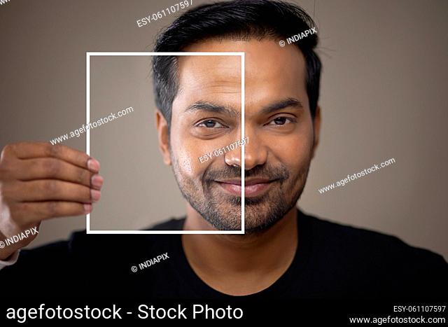 Man holding his photo next to his face, depicting his older sel