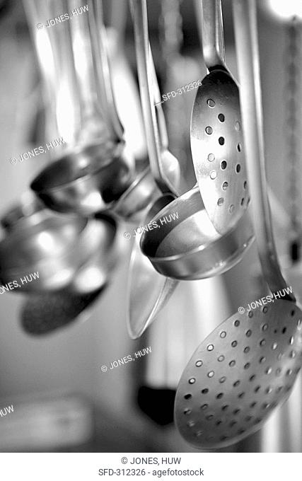 Ladles and slotted spoons hanging up in a kitchen