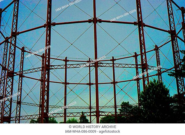A gas holder. A large container in which natural gas or town gas is stored near atmospheric pressure at ambient temperatures. London