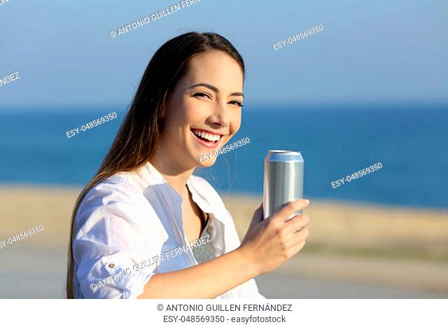 Woman holding a refreshment can looking at camera on the beach
