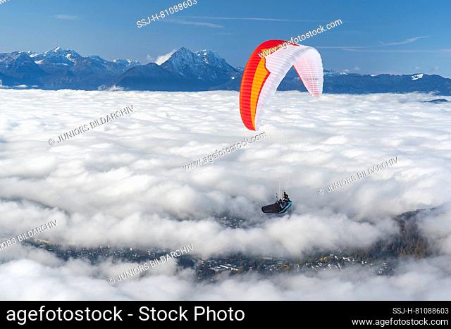 Paraglider flying over fog above the city of Salzburg, seen from the Gaisberg. Austria