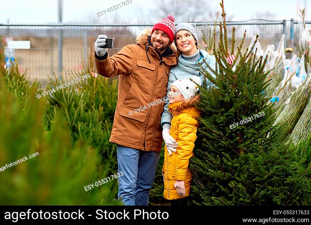 family taking selfie with christmas tree at market