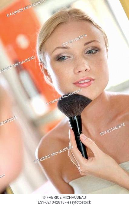Portrait of blond woman applying powder on her face