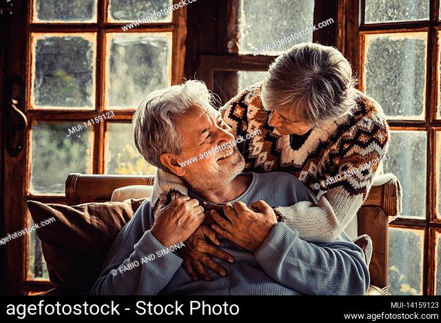 happy senior couple enjoy with love winter holidays at home hugging with joy and romance. romantic elderly lifestyle. man and woman embrace and look each other...