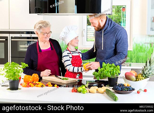Dad, grandma and kid cooking together in kitchen with the whole family
