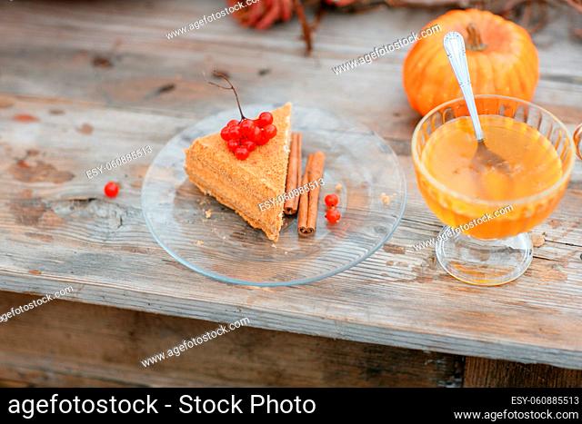 halloween inspiration. cake n wood table. Autumn still life. pumpkin, dry roses, viburnum honey cake. in a vase. twigs. on the table