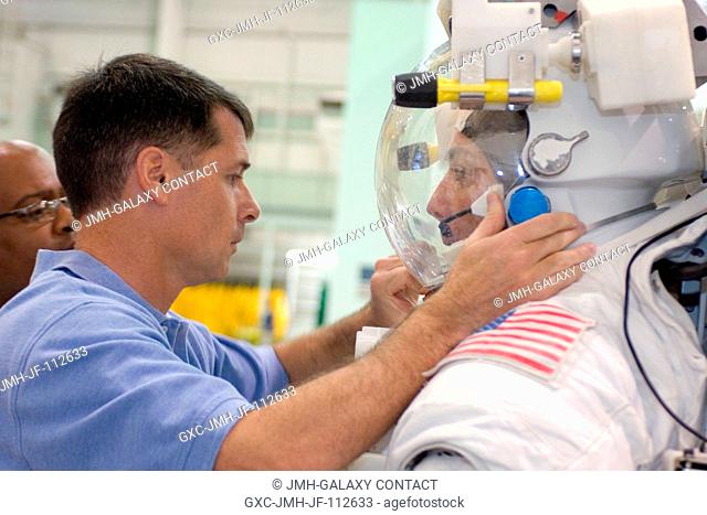Astronaut Heidemarie M. Stefanyshyn-Piper, STS-126 mission specialist, gets help with final touches in the donning of a training version of the Extravehicular...