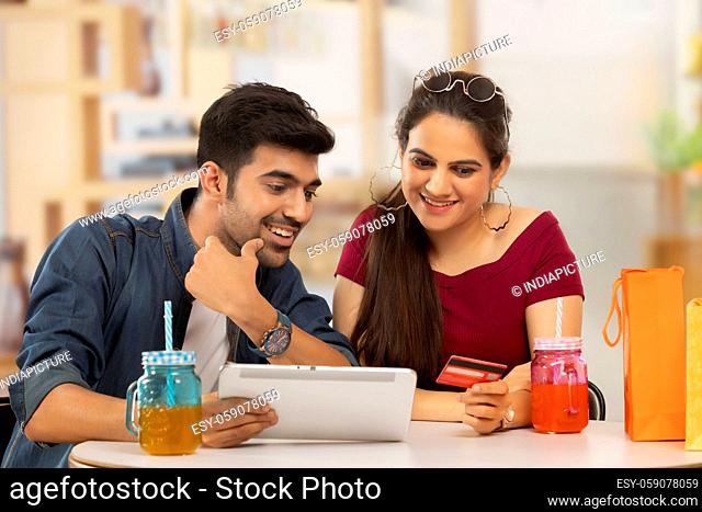 A boy with laptop and a girl with credit- card shopping online