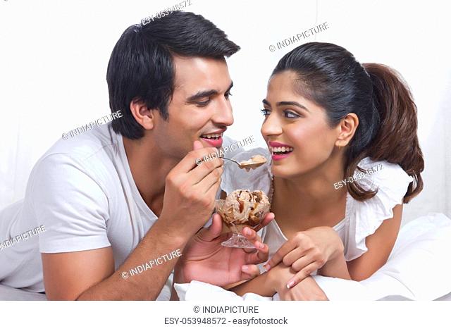 Romantic young couple having chocolate ice-cream in bed