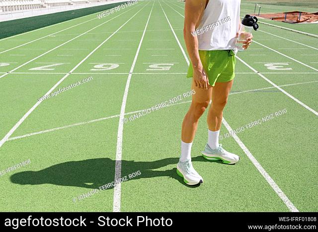 Athlete holding water bottle at sports track