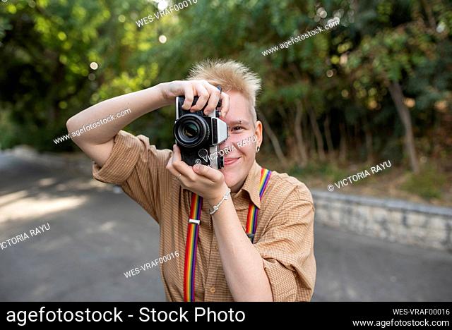 Non-binary person taking pictures with camera in park
