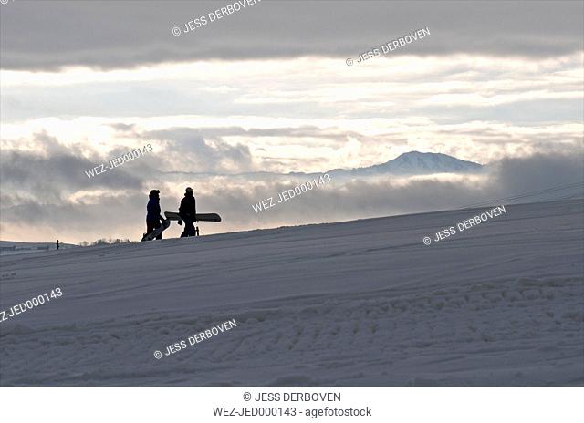 Germany, Eschach, Snowboarders walking in snow