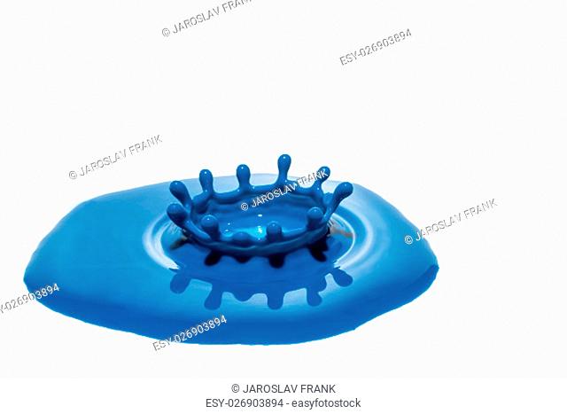 Drop of blue color created crown after falling into a puddle of blue. All is isolated on the white background