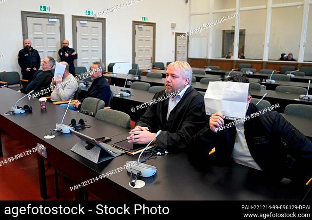 14 December 2022, Hamburg: One of the two defendants (r) sits in the courtroom in the criminal justice building and holds a piece of paper with the inscription...