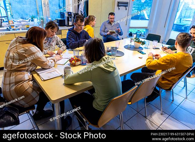 PRODUCTION - 12 January 2023, Mecklenburg-Western Pomerania, Wolgast: Nadine and Jörg Deutschmann sit with some of the children at the large table in the...
